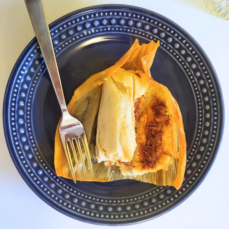 Bild der geöffneten Tamales Rojos mit Schreinefleisch und roter Salsa im Maisteig